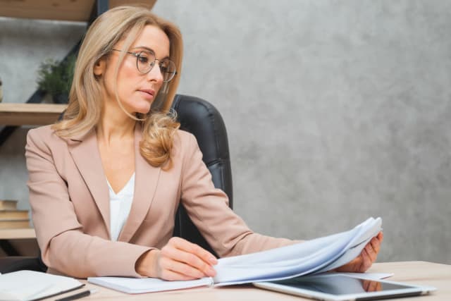 Kobieta z działu kadr sprawdza dokumenty dotyczące L4 pracownika – kontrola zwolnienia lekarskiego w firmie.